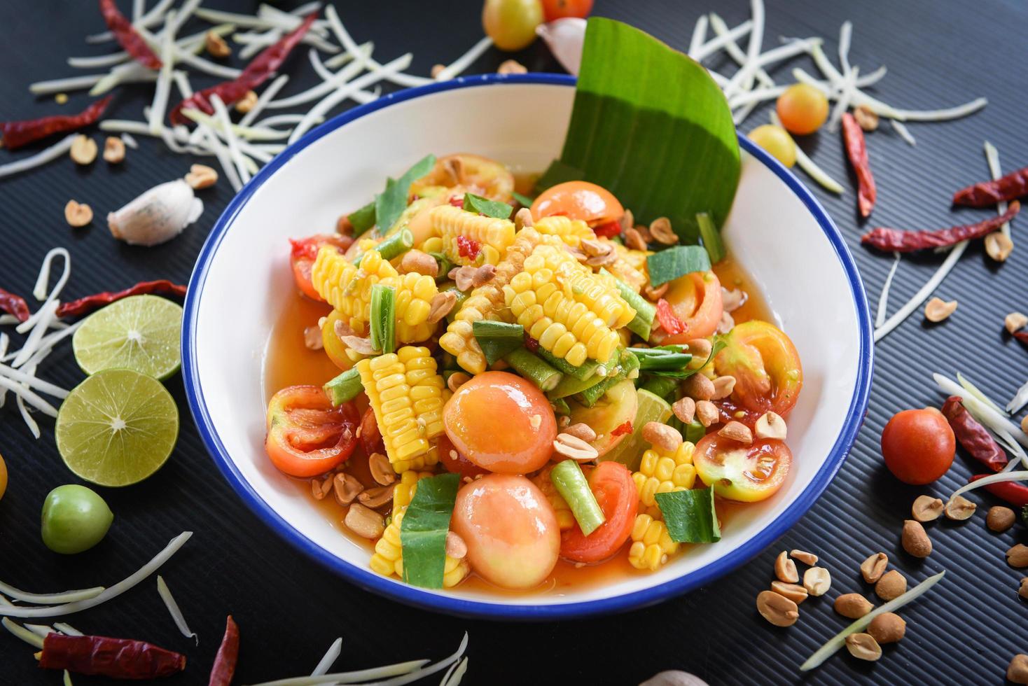 salade de maïs alimentaire menu thaï salade épicée fruits et légumes herbes et épices ingrédients avec piment tomate cacahuète ail servi sur assiette photo