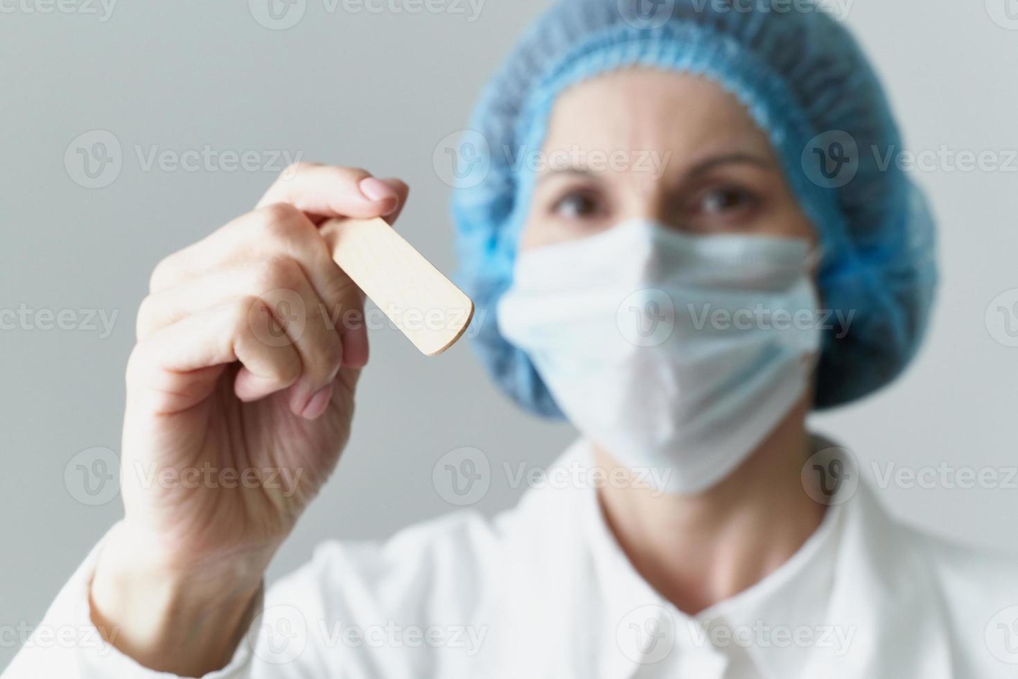 femme médecin en masque médical et contrôle uniforme de l'état de la gorge. protection contre la maladie, photo