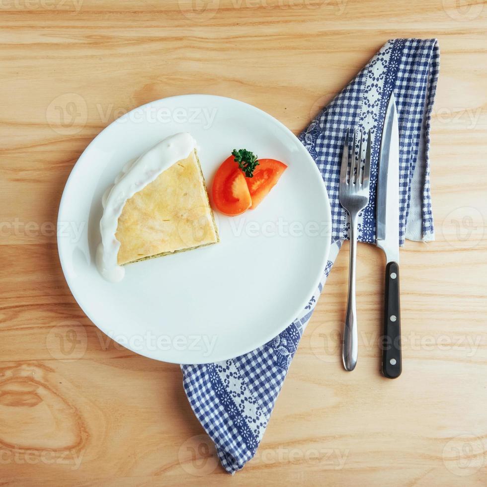 tarte aux épinards et tranche de tomate sur table en bois. photo