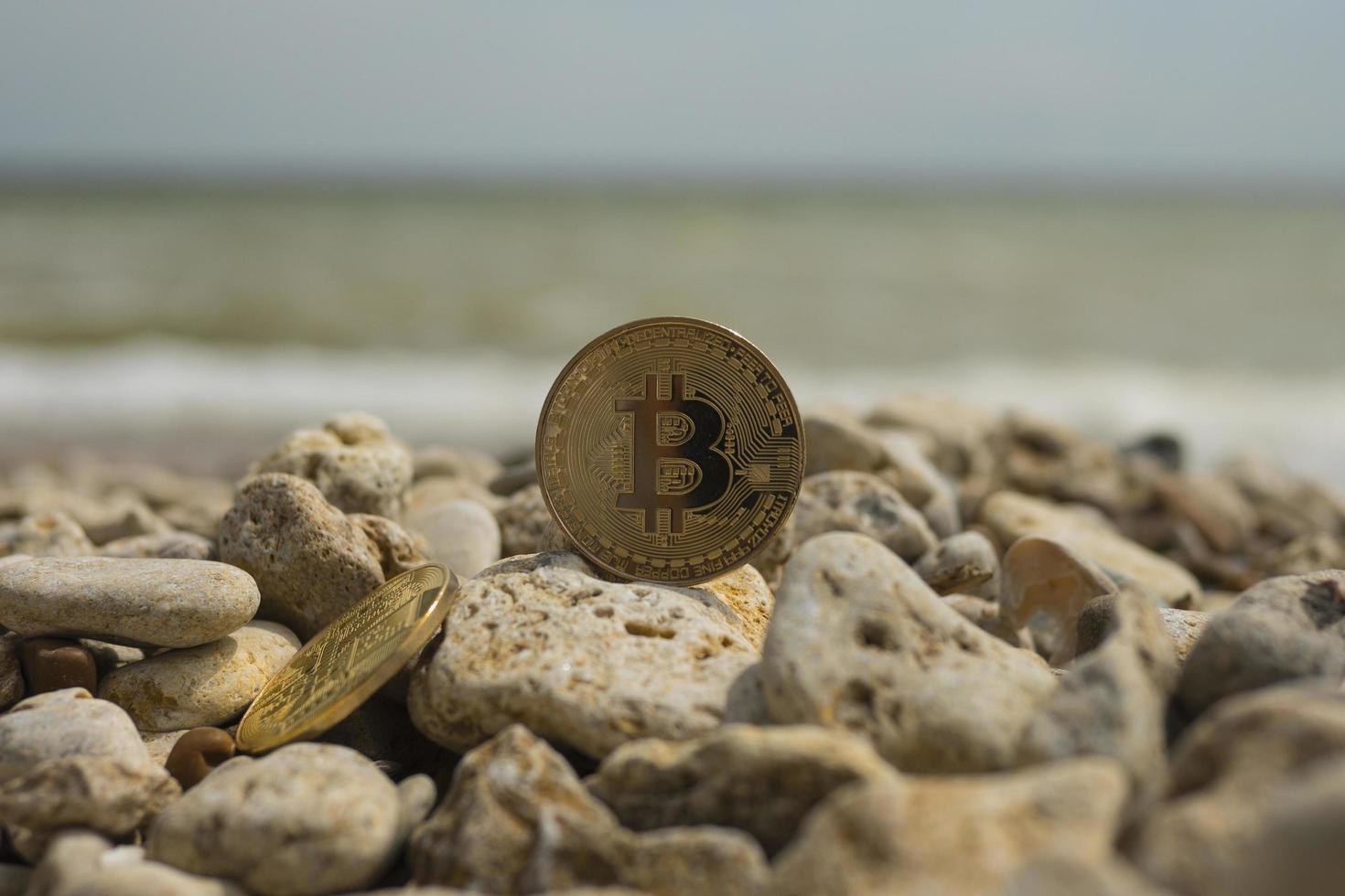 crypto-monnaie bitcoin. monnaie électronique. mer. plage d'été. pierres de mer photo