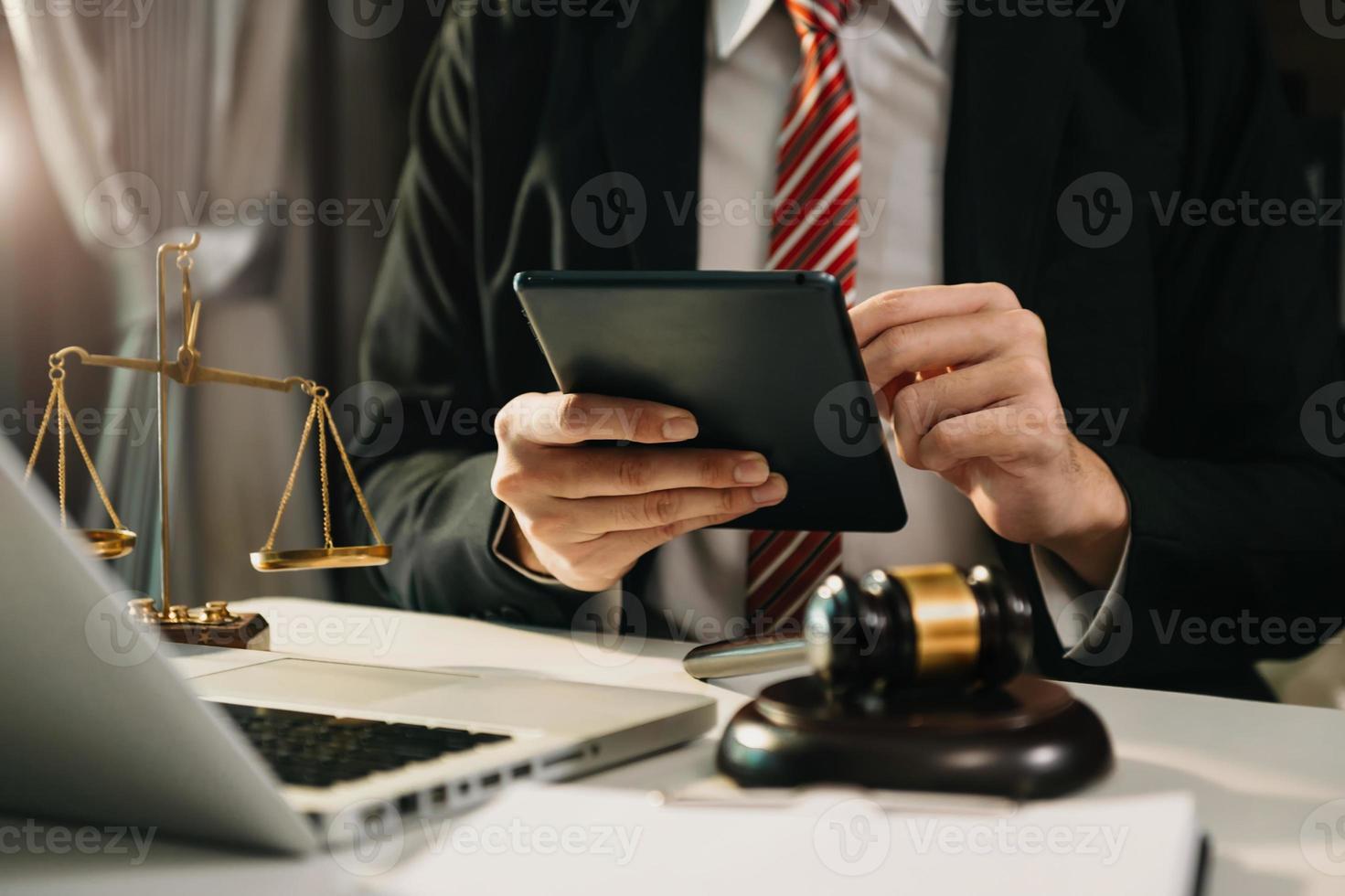 concept de justice et de droit. juge masculin dans une salle d'audience le marteau, travaillant avec un téléphone intelligent et un ordinateur portable et une tablette numérique sur une table en bois à la lumière du matin photo