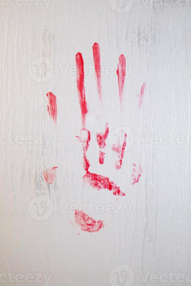 empreinte de main sanglante maculée de sang sur la fenêtre en verre dépoli photo