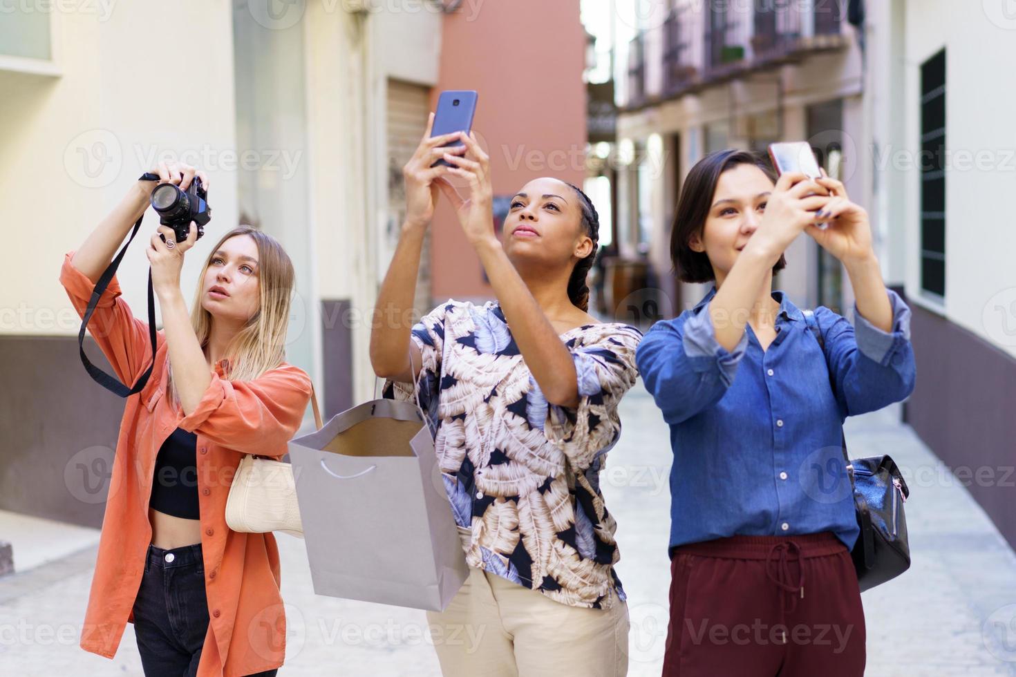 élégantes jeunes femmes diverses prenant des photos pendant les vacances dans la vieille ville