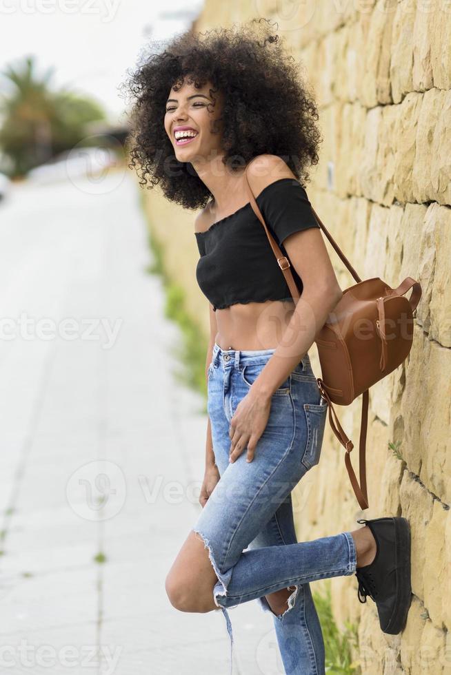 femme mixte heureuse avec des cheveux afro riant à l'extérieur photo