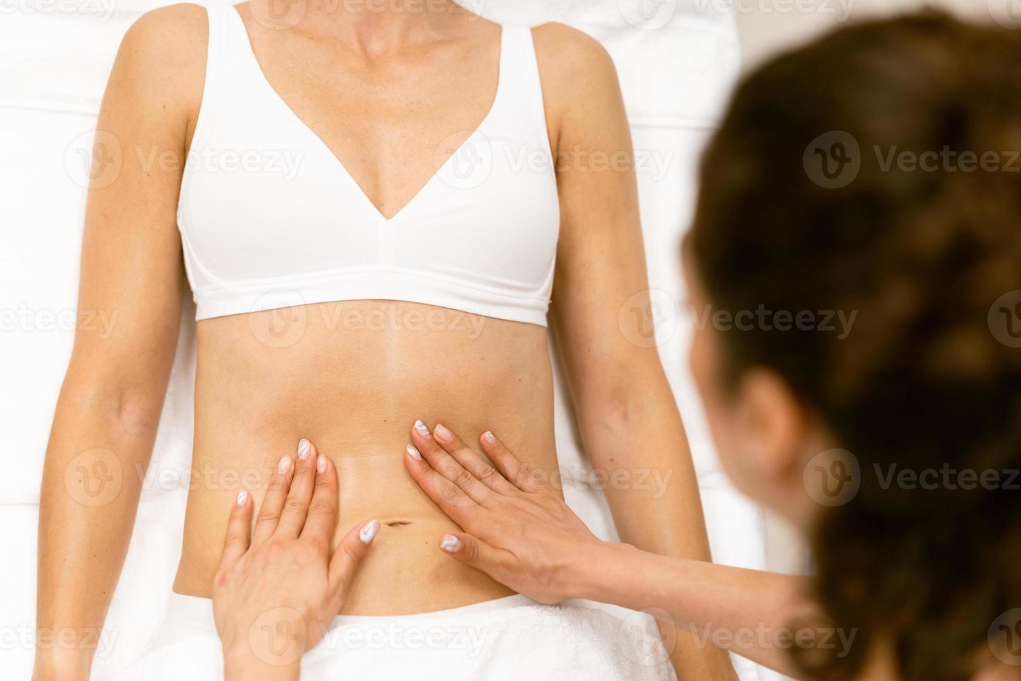 femme d'âge moyen ayant un massage du ventre dans un salon de beauté. photo