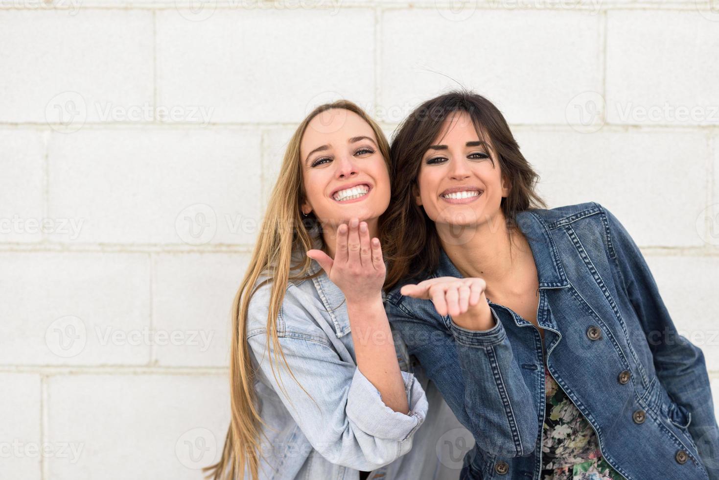 deux jeunes femmes soufflant un baiser sur un mur urbain. photo