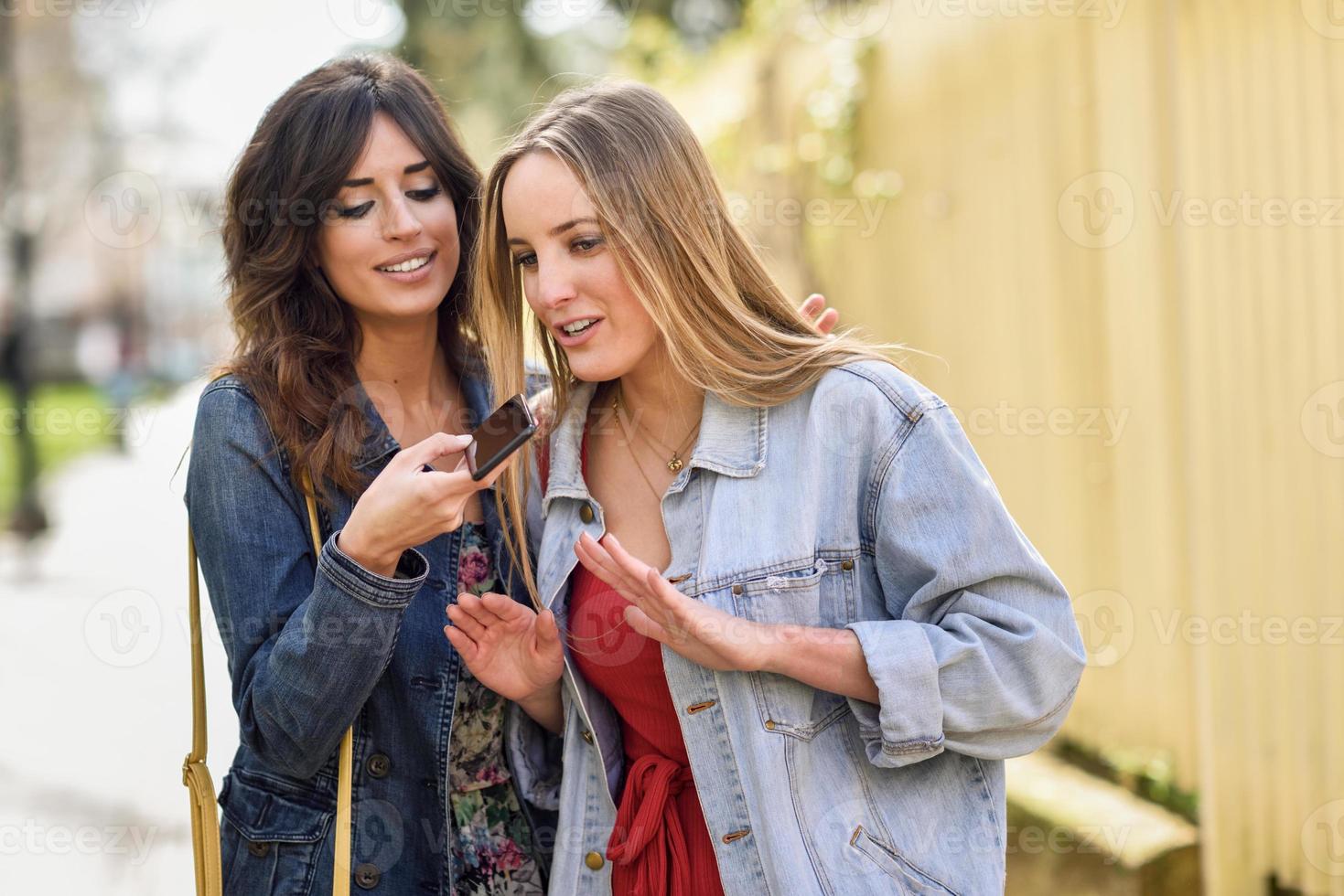 deux jeunes femmes enregistrant un message vocal avec un smartphone photo