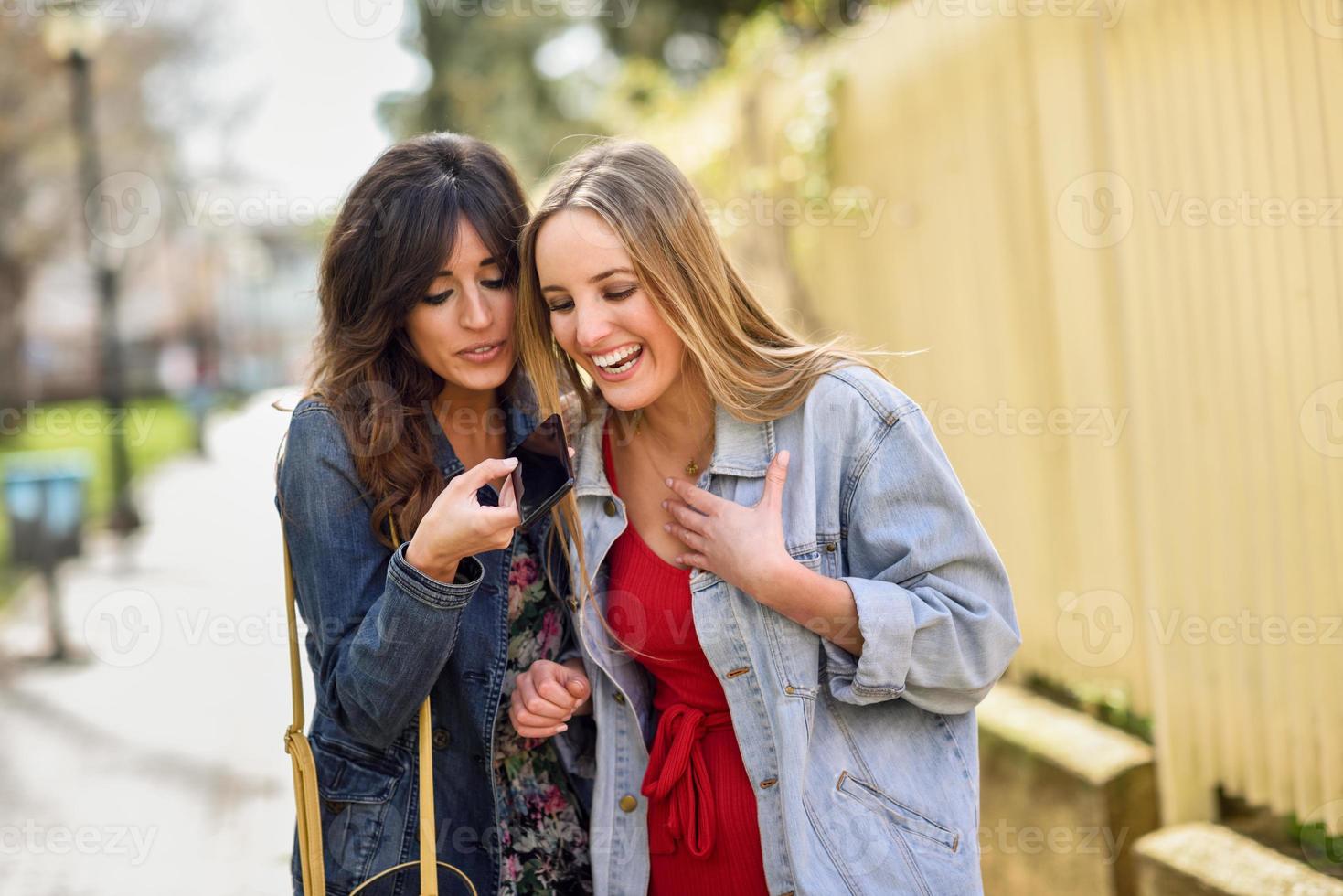 deux jeunes femmes utilisant la reconnaissance vocale du téléphone à l'extérieur photo