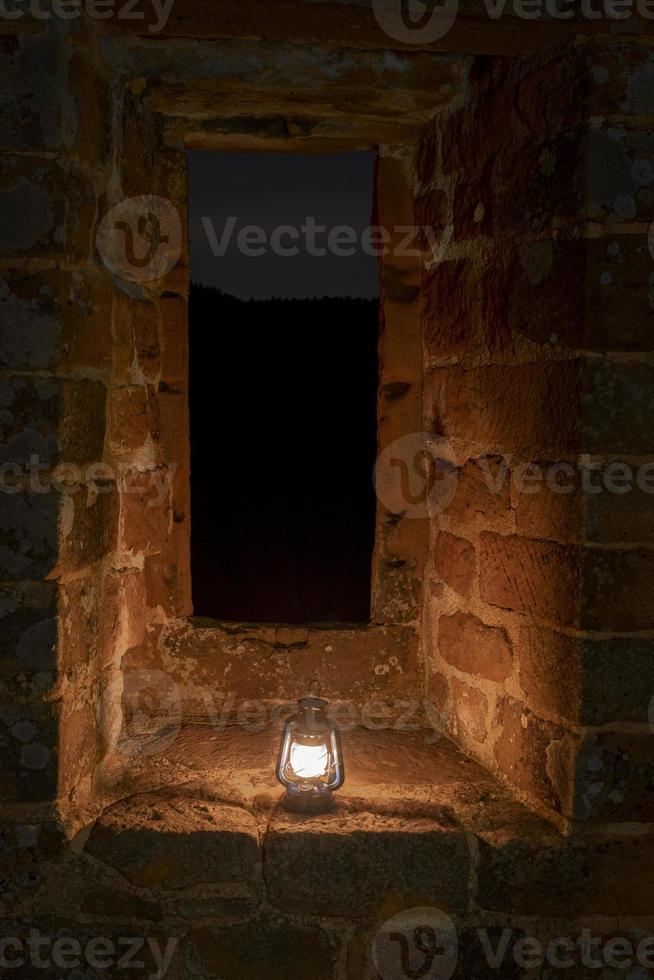 lampe à pétrole brûle la nuit sur un piédestal dans une ancienne ruine de château photo