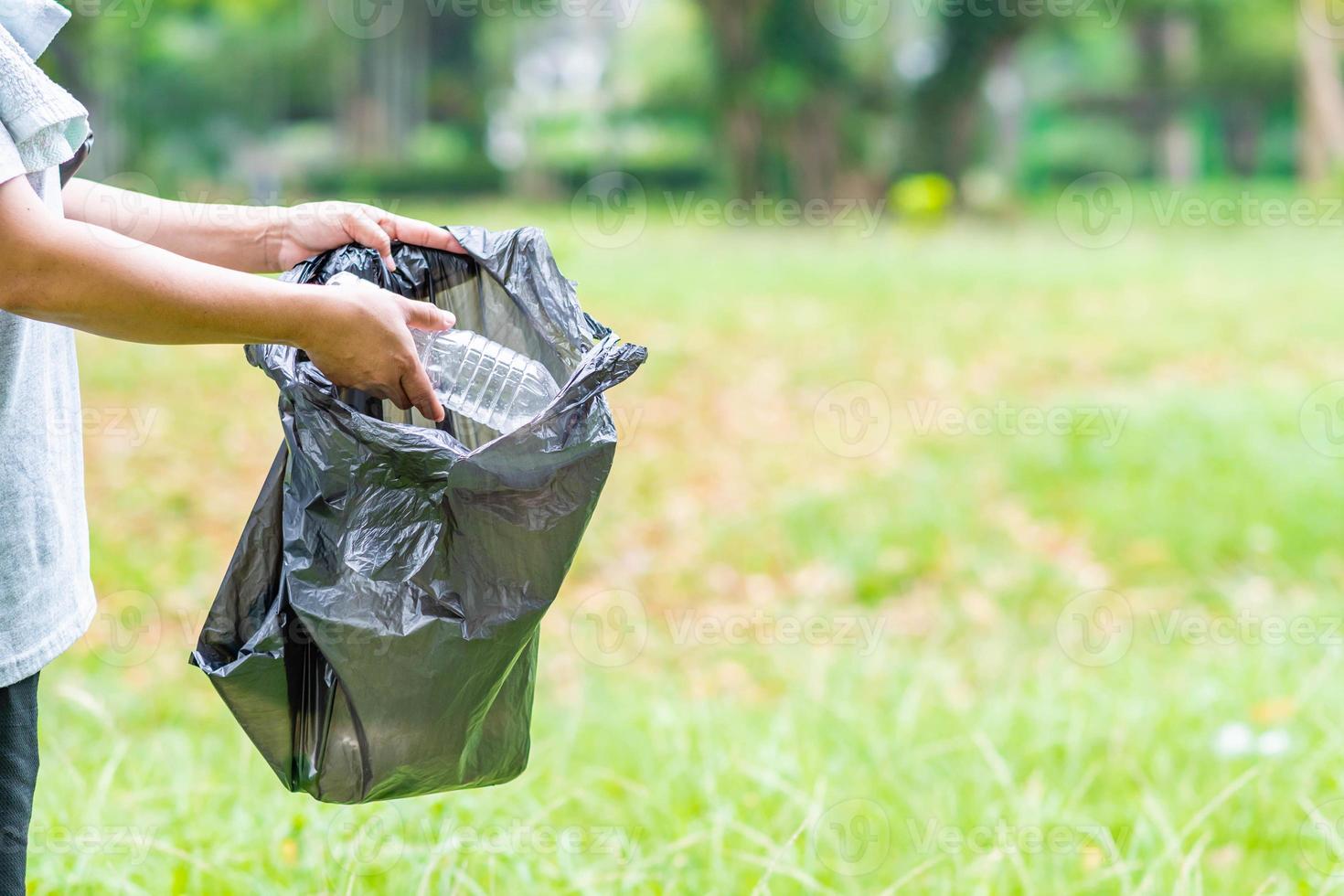 femme nettoie en ramassant des bouteilles en plastique dans le jardin. concept de protection de l'environnement, de sauvetage du monde, de recyclage, de réduction du réchauffement climatique. gros plan, arrière-plan flou, espace de copie à droite photo