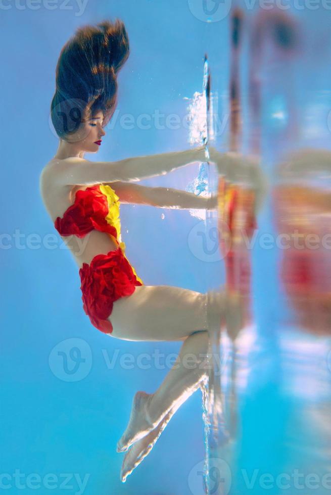 incroyable, surréaliste, incroyable, incroyable portrait sous-marin d'une femme mince et en forme en maillot de bain orange vif photo