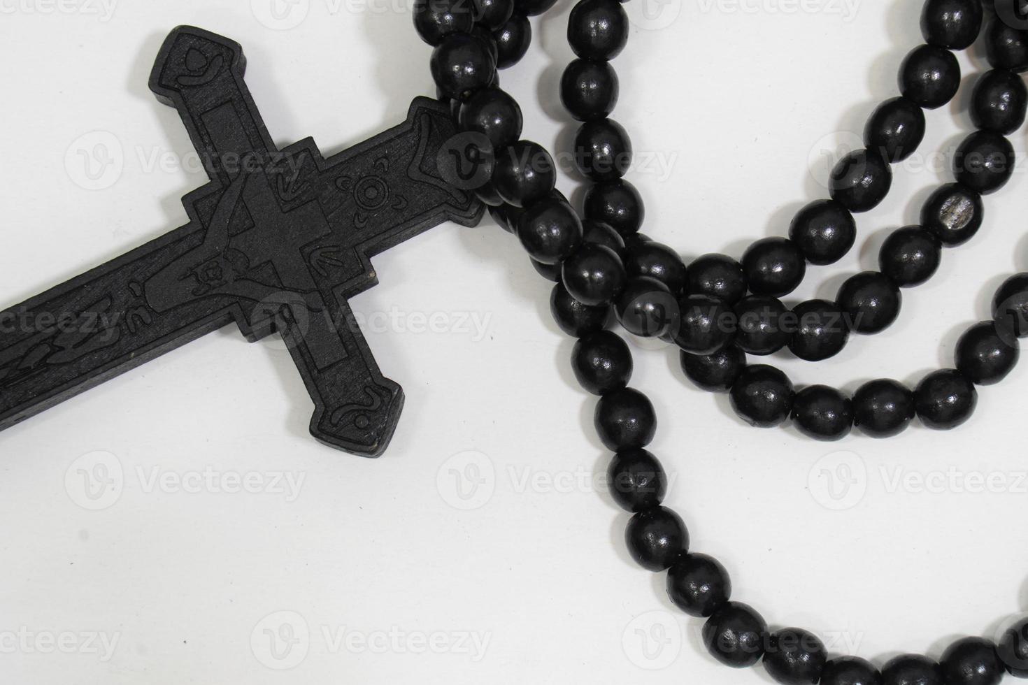 perles de chapelet avec croix en bois noir sur fond blanc, mise au point sélectionnée sur le christ, faible profondeur de champ. photo