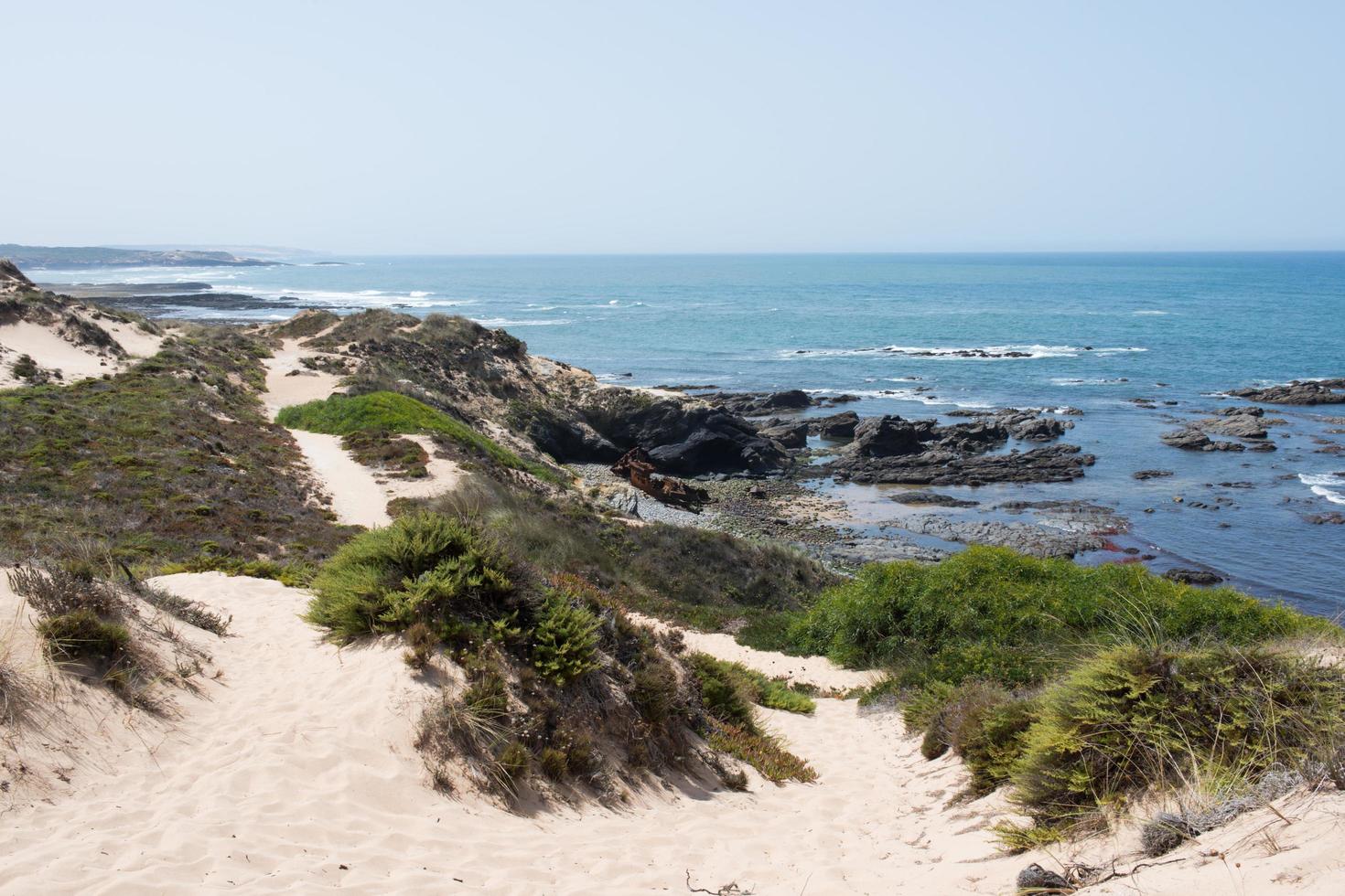 belle côte de l'alentejo. sentier pédestre sablonneux le long de la côte. vieux bateau nautique rouillé. journée ensoleillée. photo