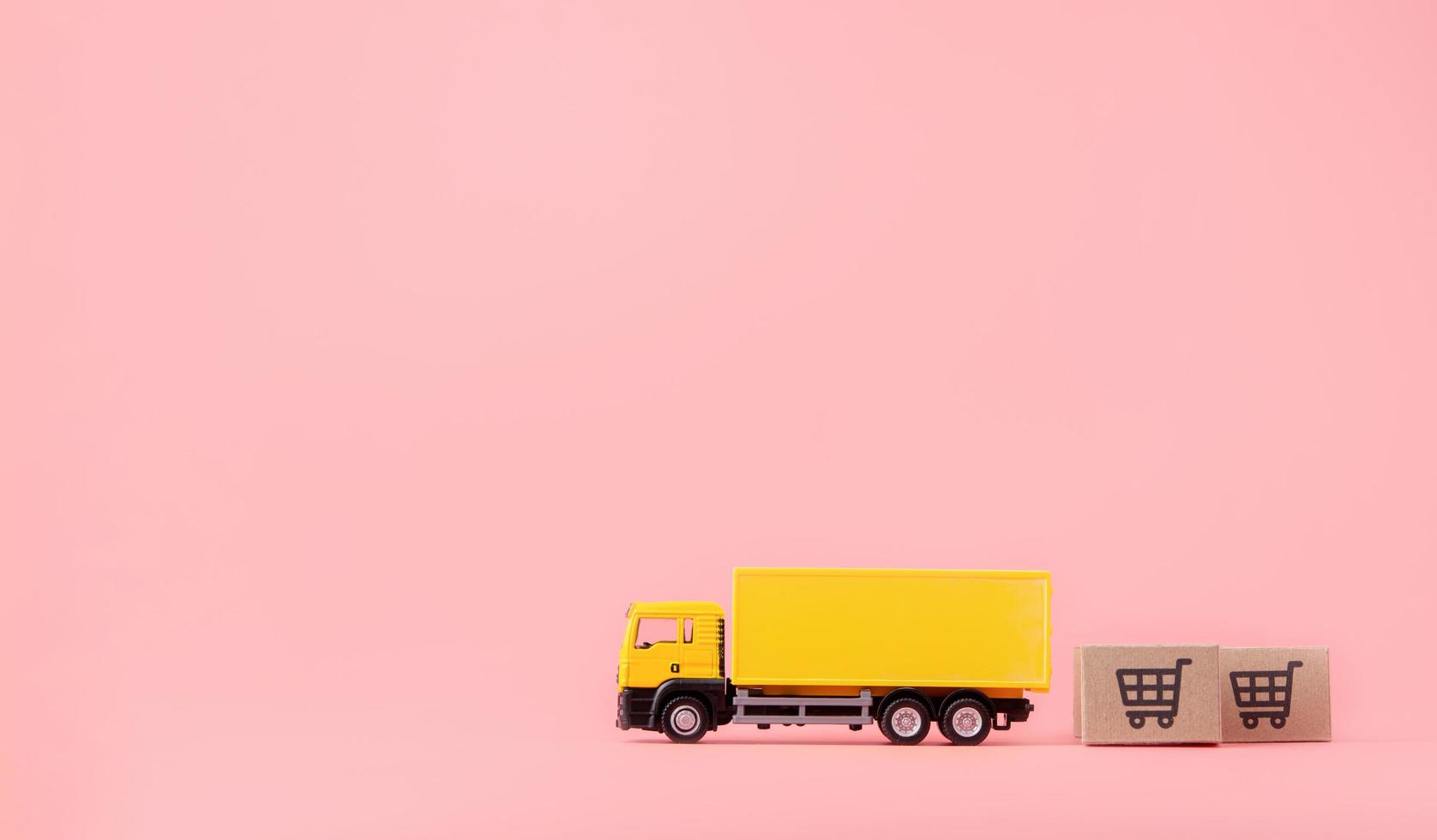 logistique et service de livraison - camion de fret et cartons en papier ou colis avec un logo de panier sur fond rose. service d'achat sur le web en ligne et propose la livraison à domicile. avec espace de copie photo