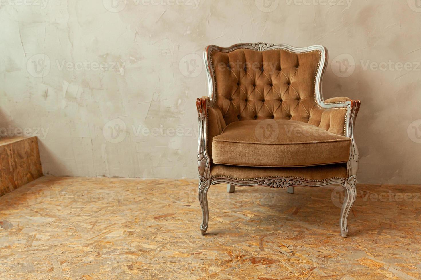 belle salle intérieure propre de luxe classique de style grunge avec fauteuil baroque marron. Chaise marron-gris antique vintage debout à côté du mur. conception de maison minimaliste. photo