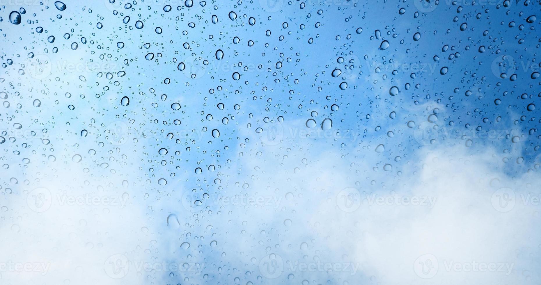 gouttes de pluie sur la fenêtre en verre bleu avec fond de brouillard. photo