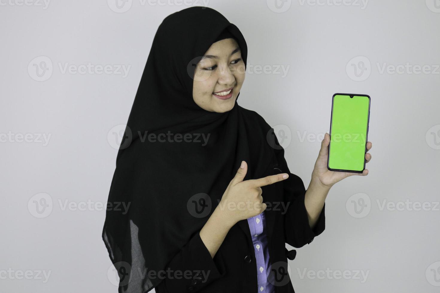 heureuses femmes d'affaires islamiques asiatiques pointant et montrant un écran vide sur le téléphone. photo