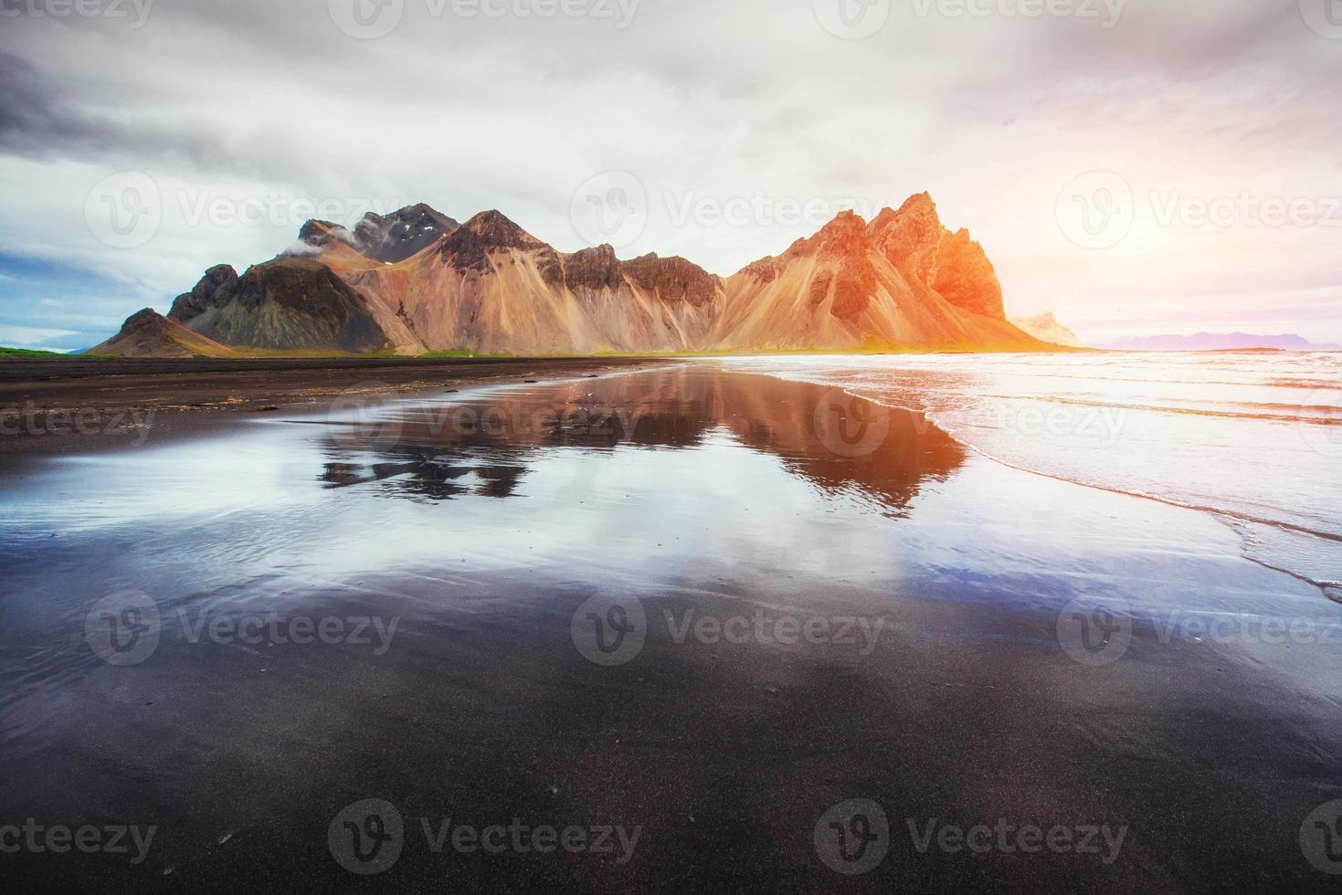 des montagnes étonnantes se reflètent dans l'eau au coucher du soleil. stoksnes, ic photo