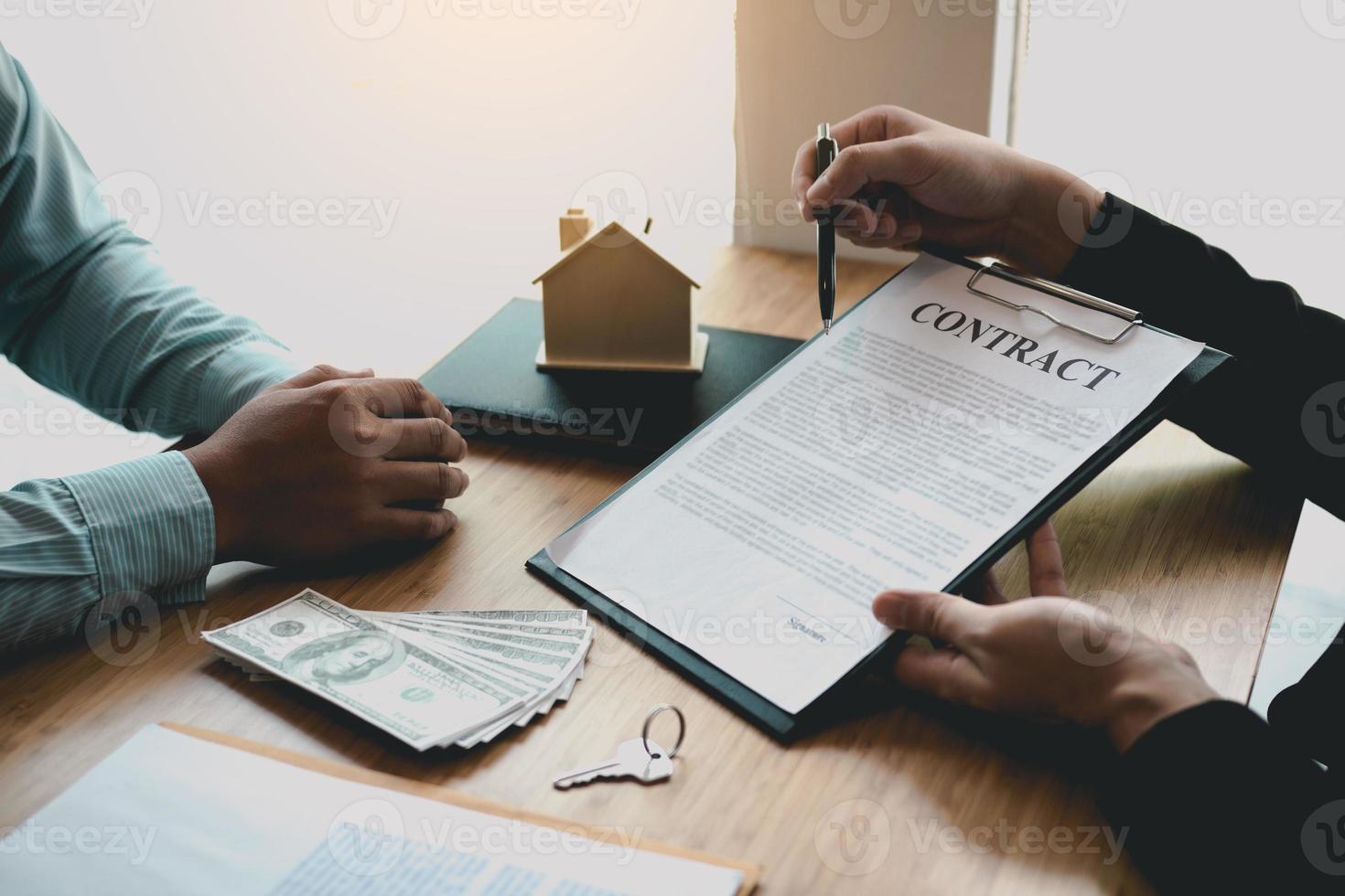 les agents utilisent des stylos pointant vers les contrats d'assurance et sont expliqués aux clients au bureau. photo