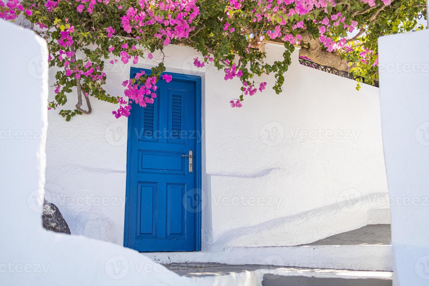 fond de voyage fantastique, paysage urbain de santorin. porte bleue avec escaliers et fleurs, architecture blanche sous ciel bleu. concept de vacances de vacances d'été idyllique. merveilleuses vibrations de luxe d'été photo