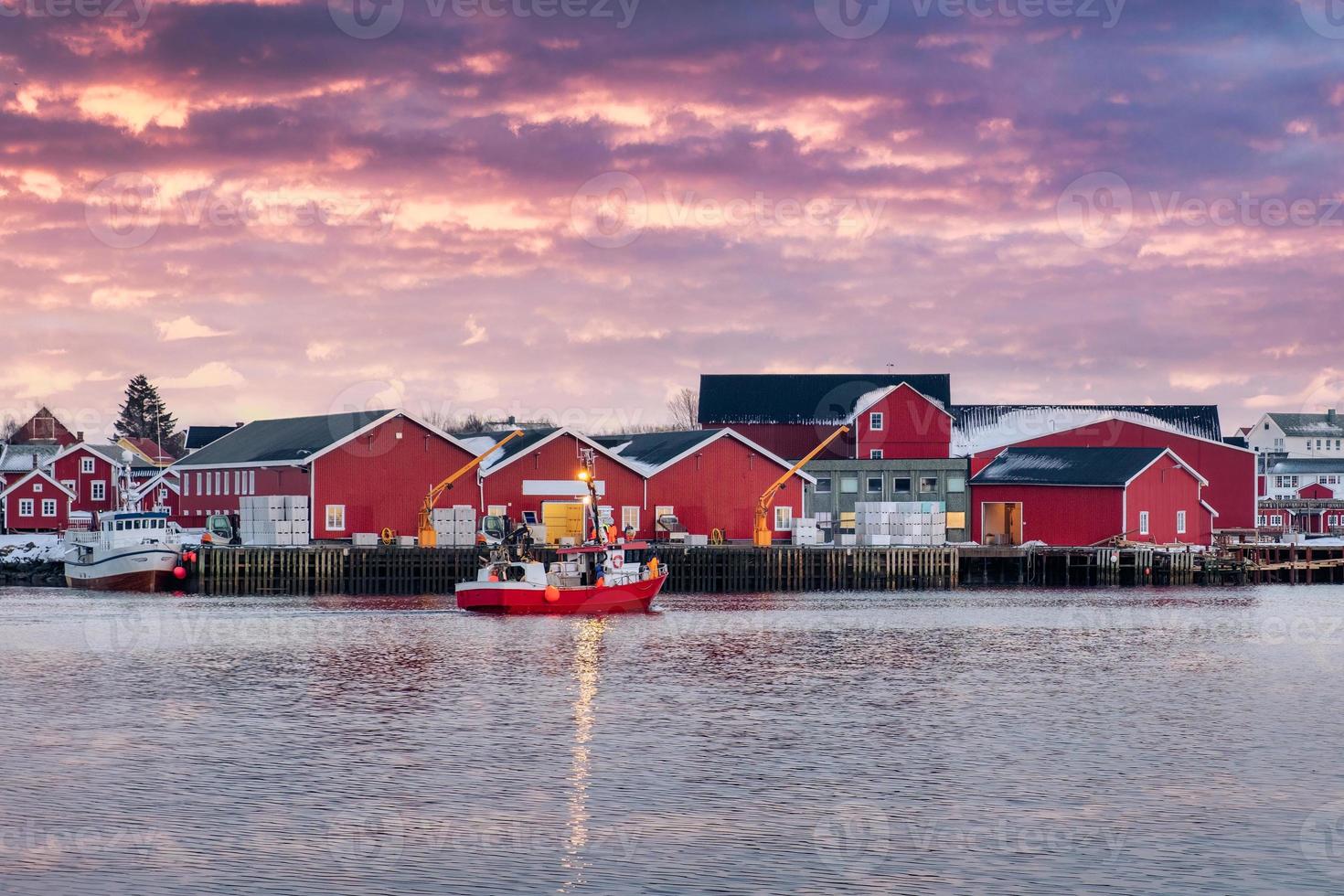 beau village de pêcheurs de rorbuer et bateau de pêche sur la côte au coucher du soleil à la ville de reine, îles lofoten photo