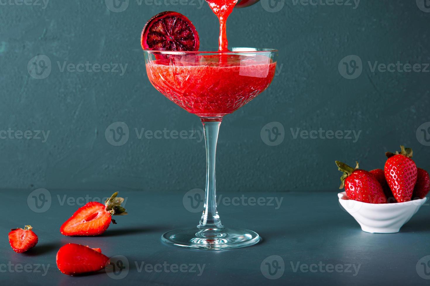 une main anonyme verse un cocktail de fraises ou du jus d'une tasse ou d'un shaker. inclut l'espace de copie. photo