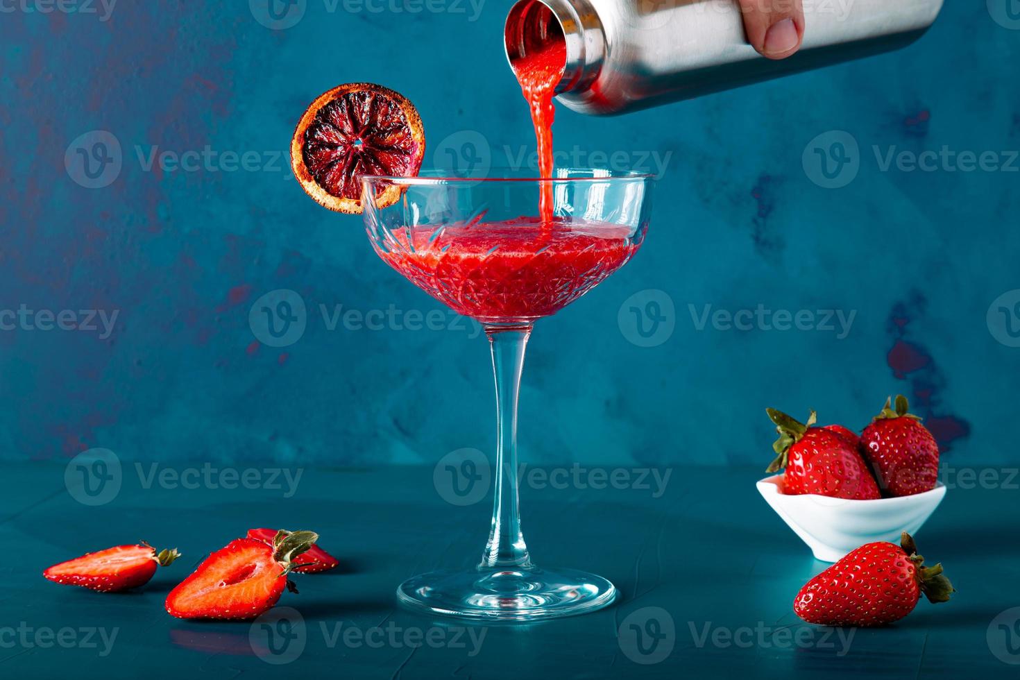 une main anonyme verse un cocktail de fraises ou du jus d'une tasse ou d'un shaker. inclut l'espace de copie. photo