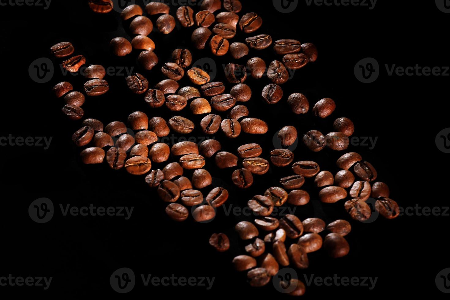 grains de café dispersés. café parfumé sur la table. le café est grand. café sur fond noir. photo