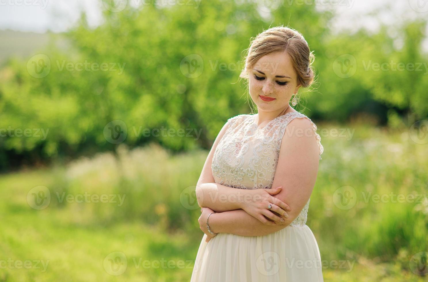 jeune fille en surpoids à la robe beige posée fond jardin de printemps. photo