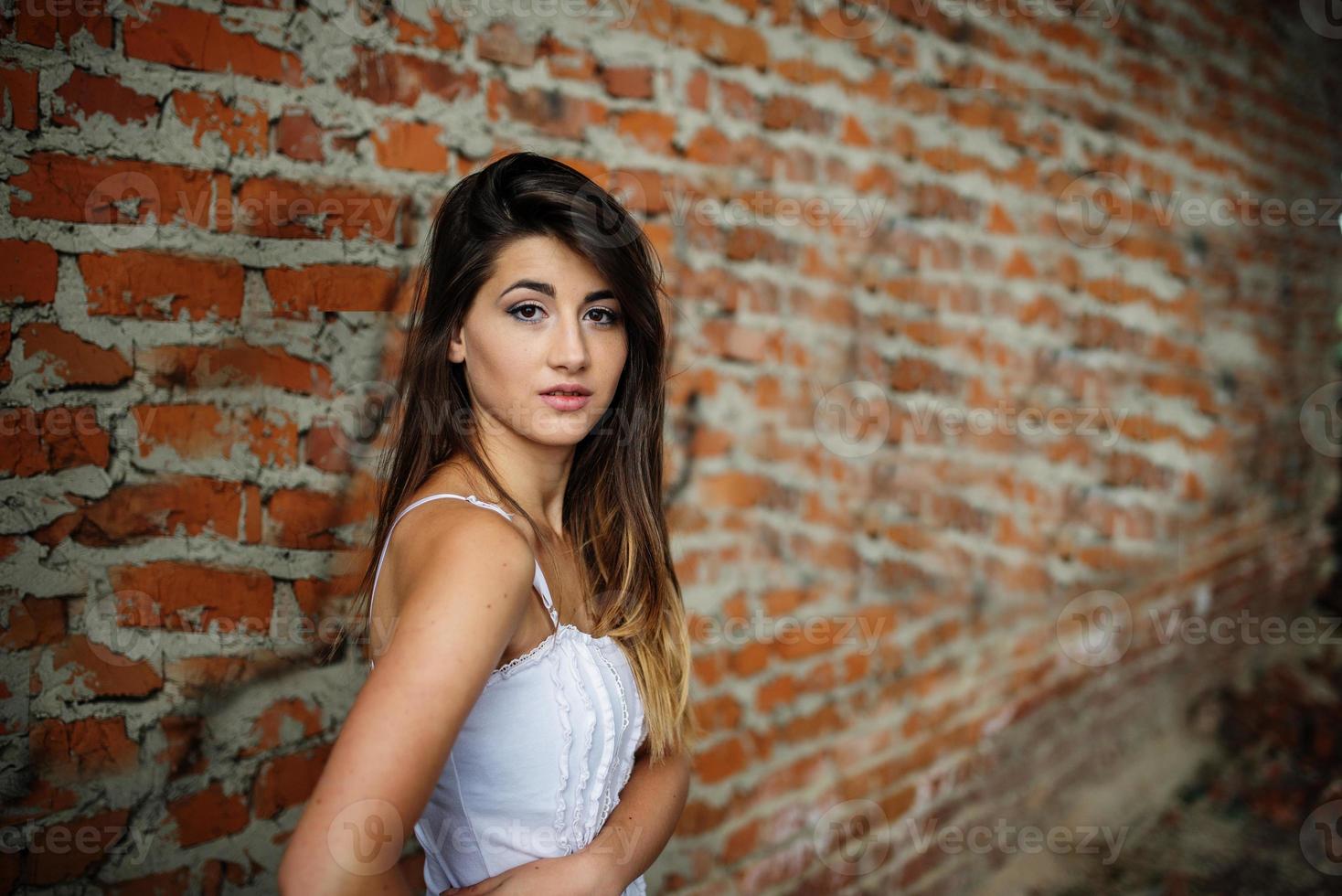 portrait de mur de briques de fond jeune jolie fille brune. photo