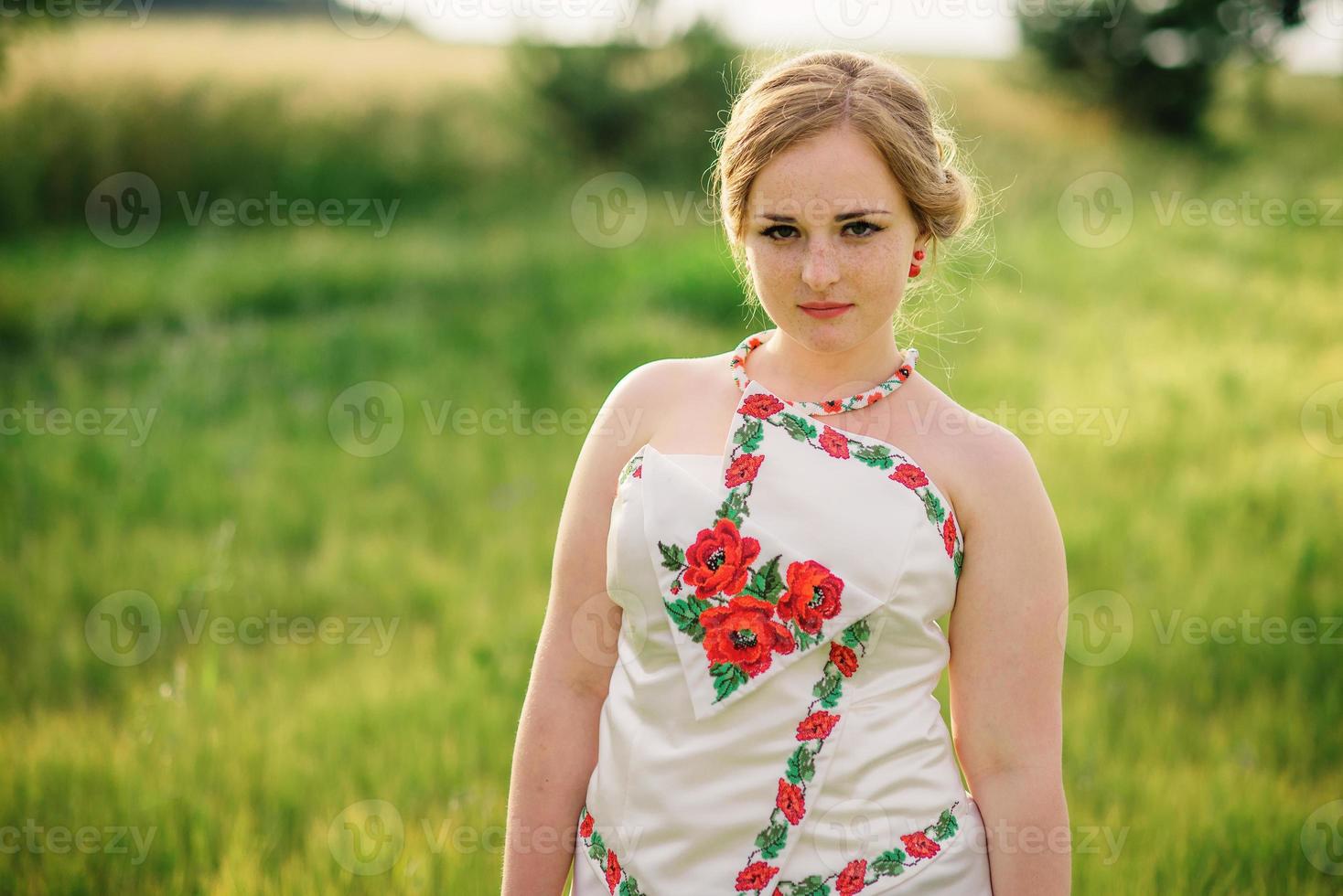 jeune fille à la robe nationale ukrainienne posée au champ de couronne. photo