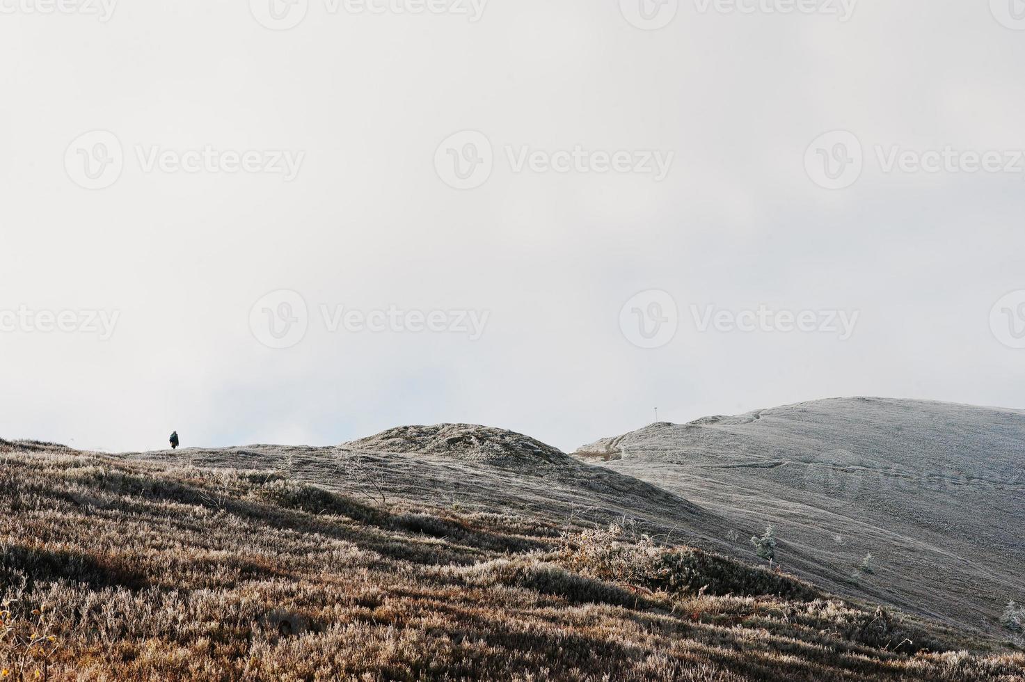 homme au sommet de la colline de givre, marchant vers le haut. paysages incroyables de personnes et de montagne. photo