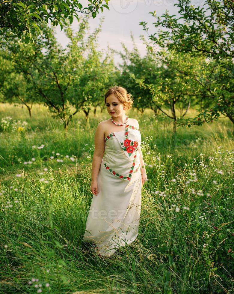 jeune fille à la robe nationale ukrainienne posée au jardin de printemps. photo