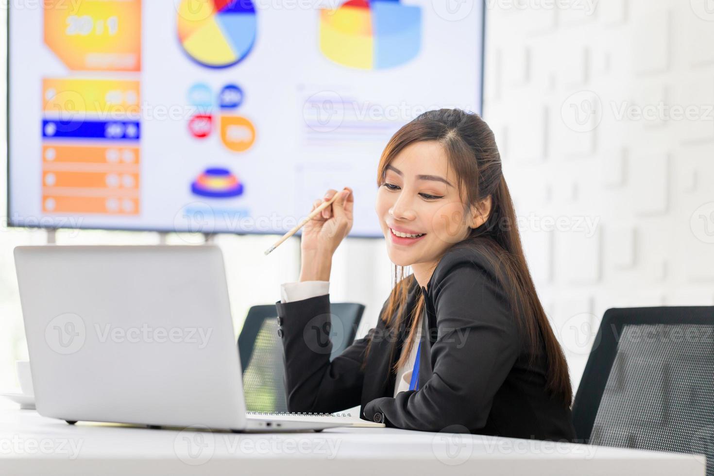 portrait d'une jeune femme d'affaires travaillant sur un ordinateur portable, d'une femme faisant du travail de bureau dans un bureau moderne, d'un employé de bureau attrayant assis au bureau photo
