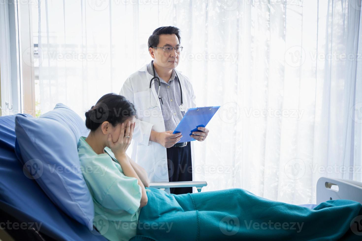 les médecins posent des questions et expliquent la maladie à une patiente allongée dans son lit dans un hôpital. photo