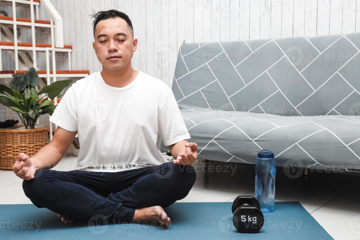 homme asiatique pratiquant le yoga ou la méditation à la maison photo