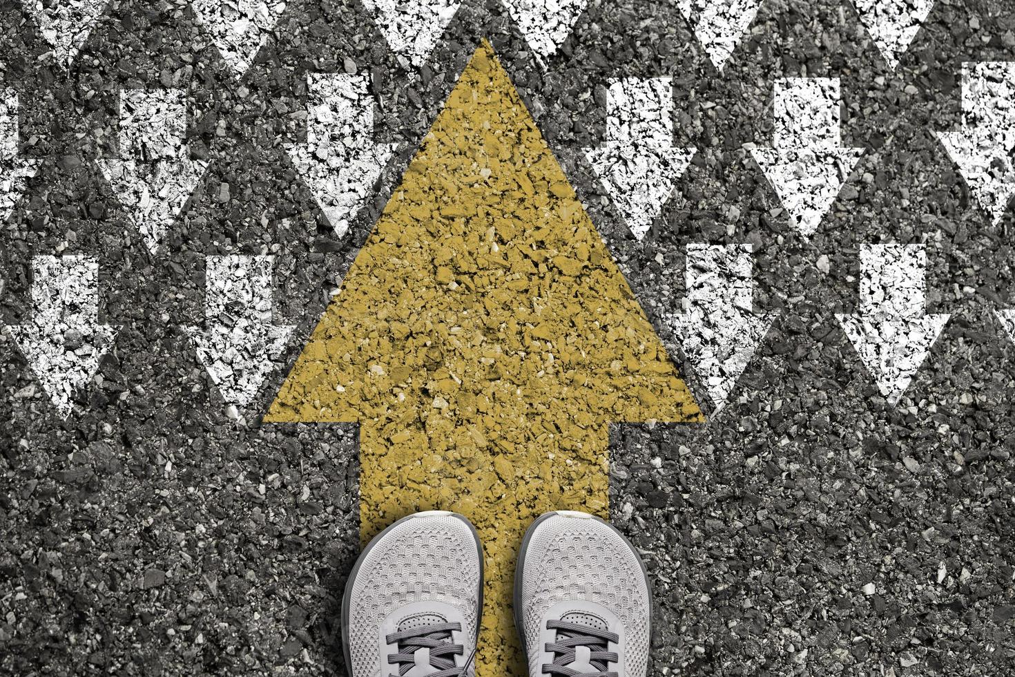 pensée différente et concept de perturbation des affaires et de la technologie. grosse flèche jaune sens opposé avec flèche blanche sur l'asphalte de la route. photo