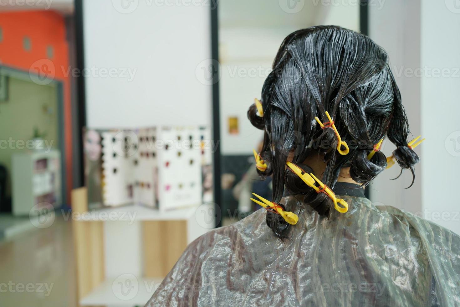 coiffeur professionnel faisant une coloration et un traitement des cheveux dans un magasin de beauté et de salon. femme changeant de couleur de cheveux dans un magasin de salon professionnel. photo