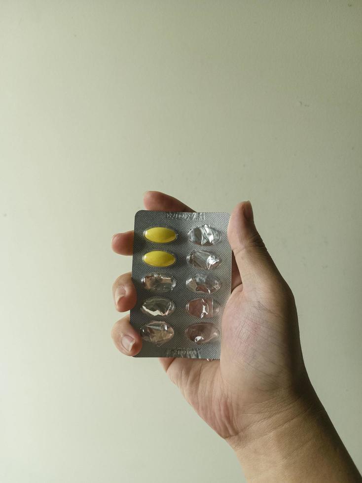 Image en gros plan d'un homme tenant et cueillant un médicament jaune à la main photo