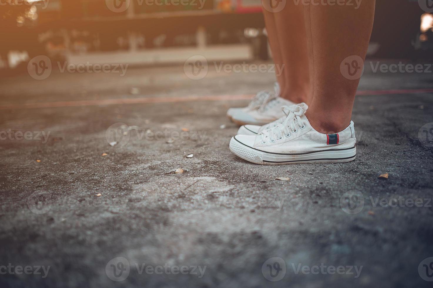 deux filles debout l'une à côté de l'autre portant des chaussures blanches. photo