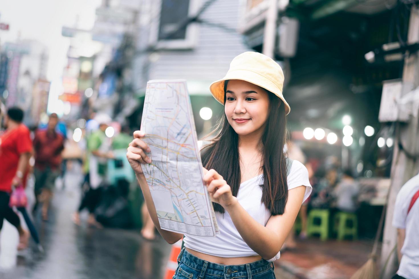 une jeune voyageuse asiatique adulte utilise la carte pour explorer la zone. photo