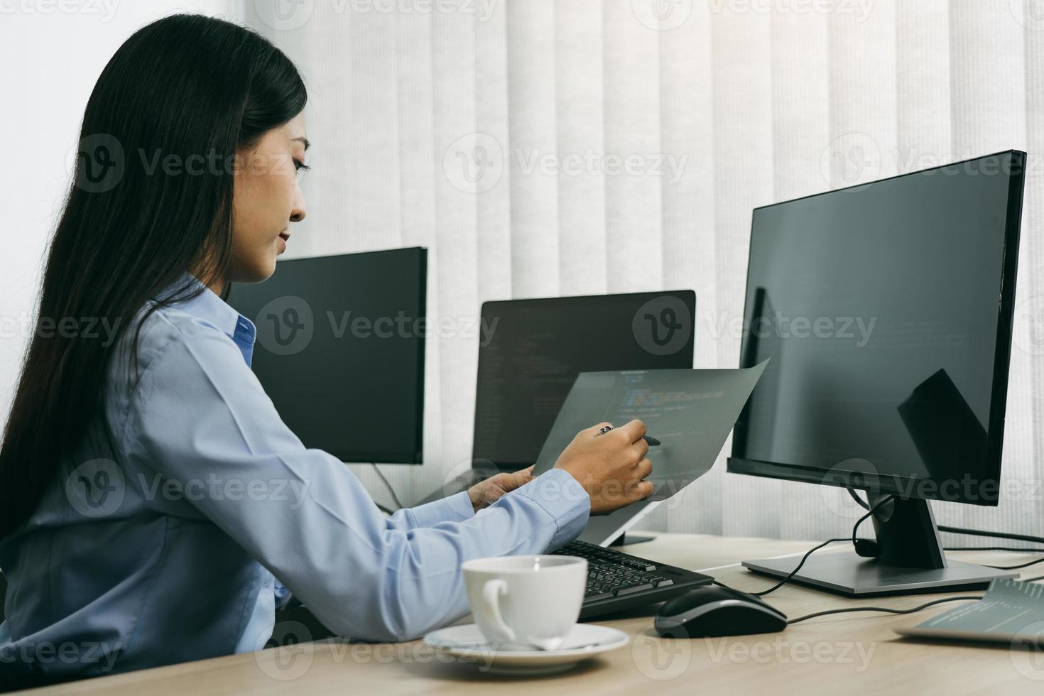 Développeurs de logiciels de femme asiatique assis devant des ordinateurs regardant des codes informatiques sur l'écran. photo