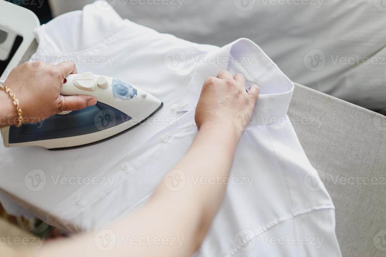 chemise blanche de repassage à la main féminine sur une planche à repasser photo