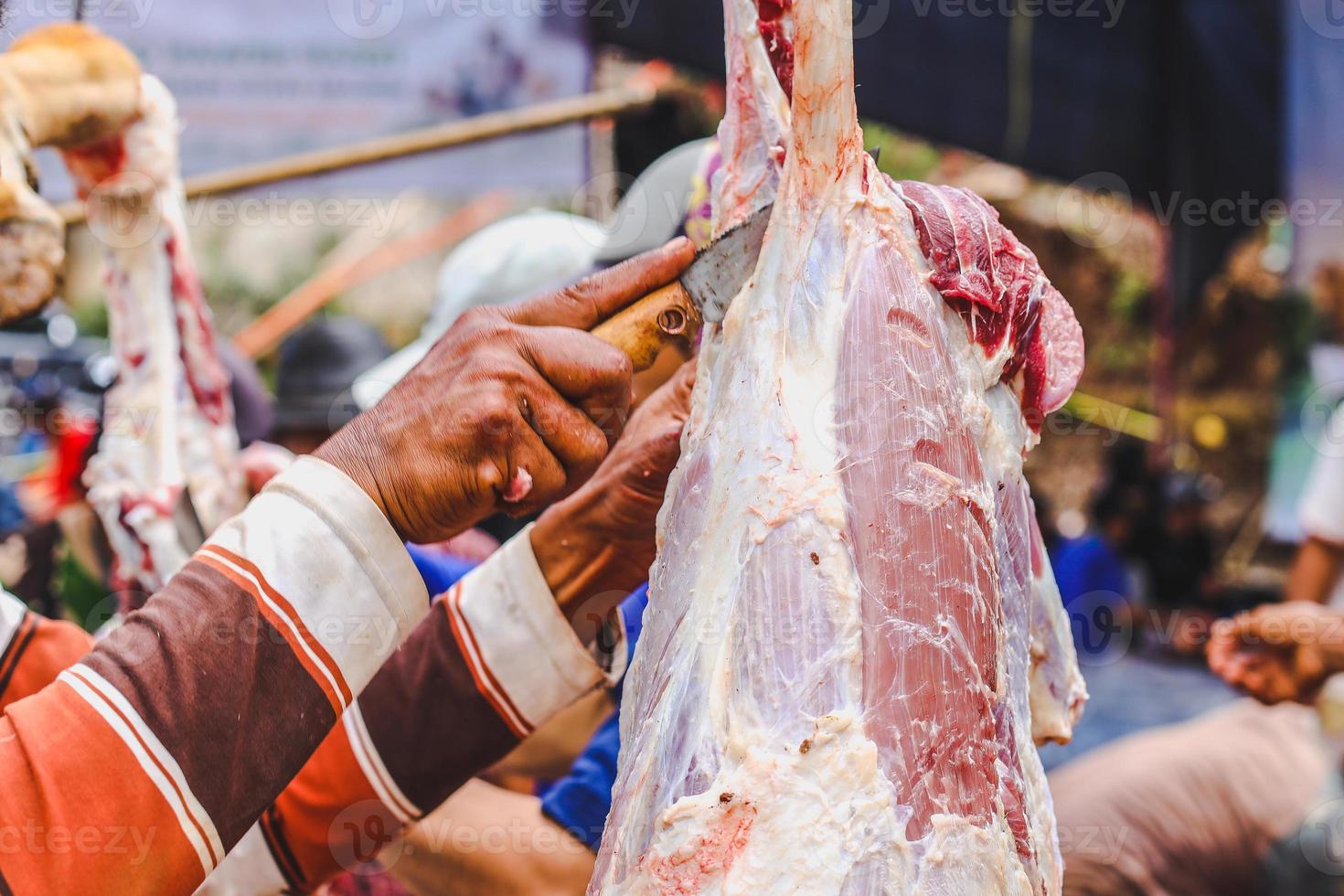 mains coupant de la viande lors de la célébration du jour islamique de l'aïd al-adha photo