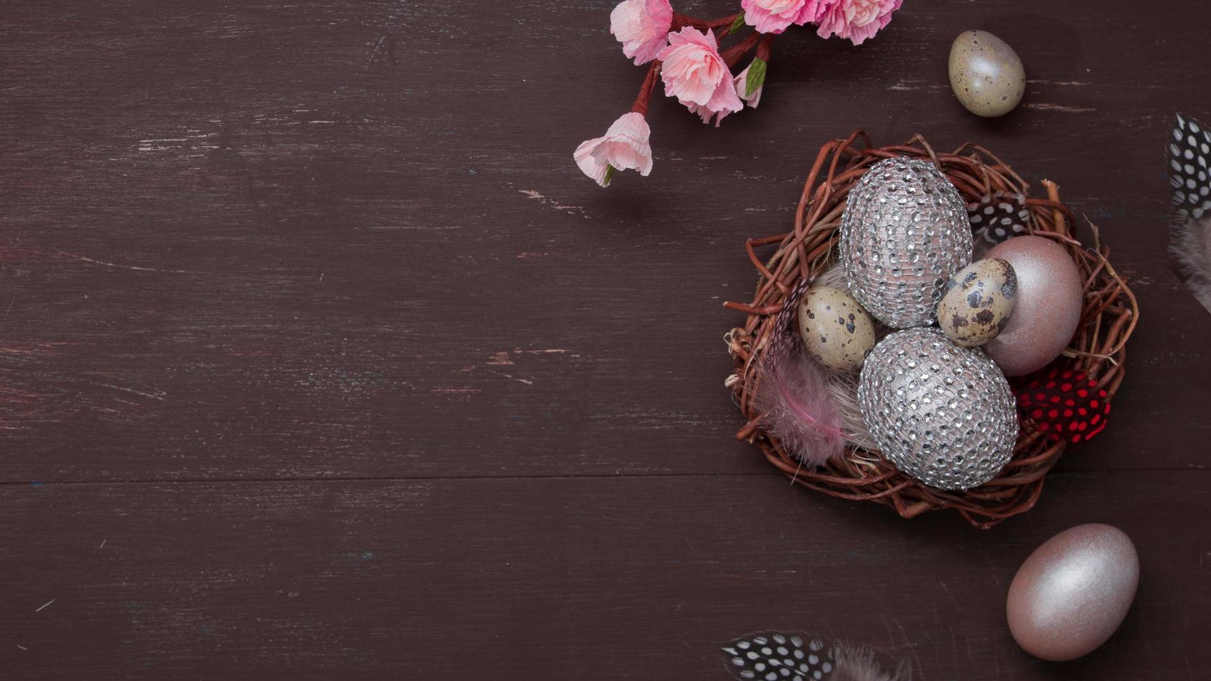 nid de pâques à plat et oeufs sur fond marron avec espace de copie de fleurs de fleurs roses photo