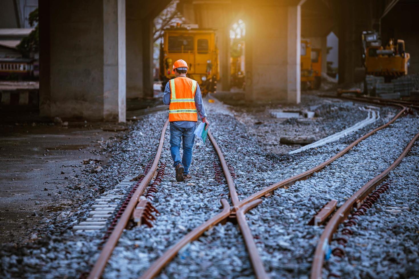 ingénieur chemin de fer en cours de vérification du processus de construction essai de train et vérification des travaux ferroviaires sur la gare avec communication radio .ingénieur portant un uniforme de sécurité et un casque de sécurité au travail. photo