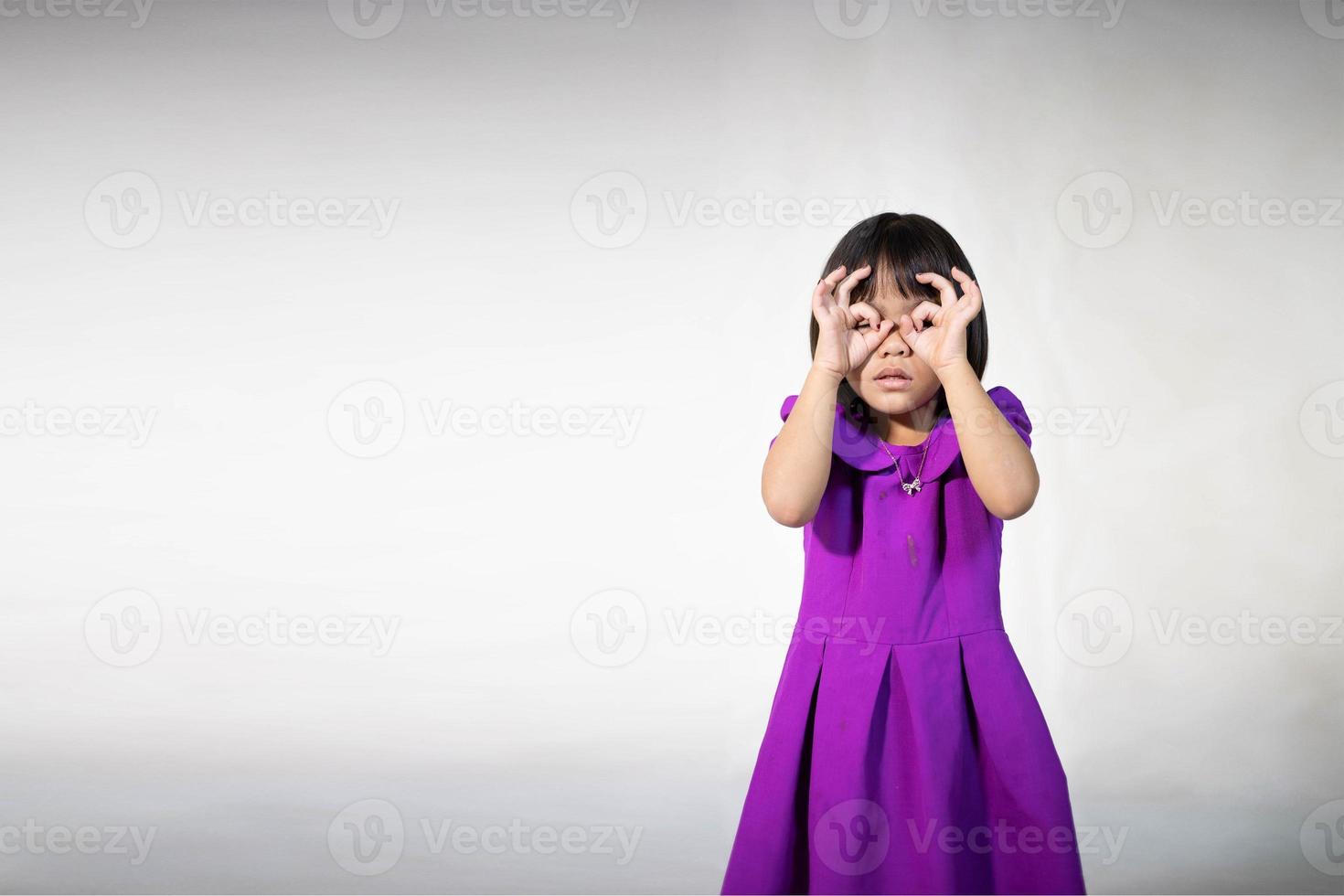 portrait de jolie fille asiatique d'une petite fille joyeuse en t-shirt gris regardant la caméra et fond isolé clignotant. fille caucasienne émotionnelle. enfant heureux photo