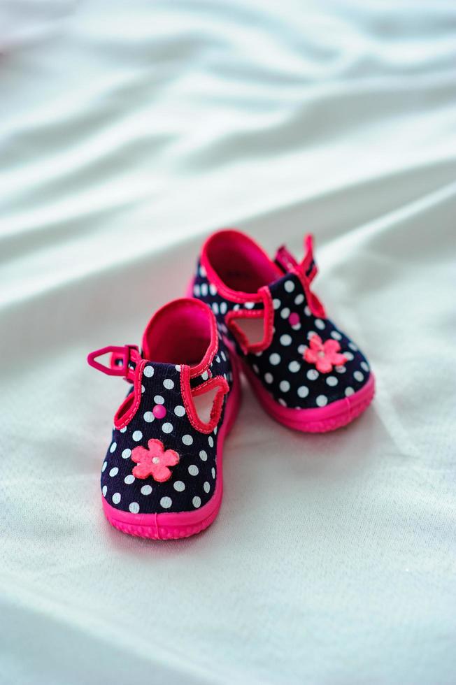 la première paire de sandales pour enfants sur fond de tissu blanc. photo