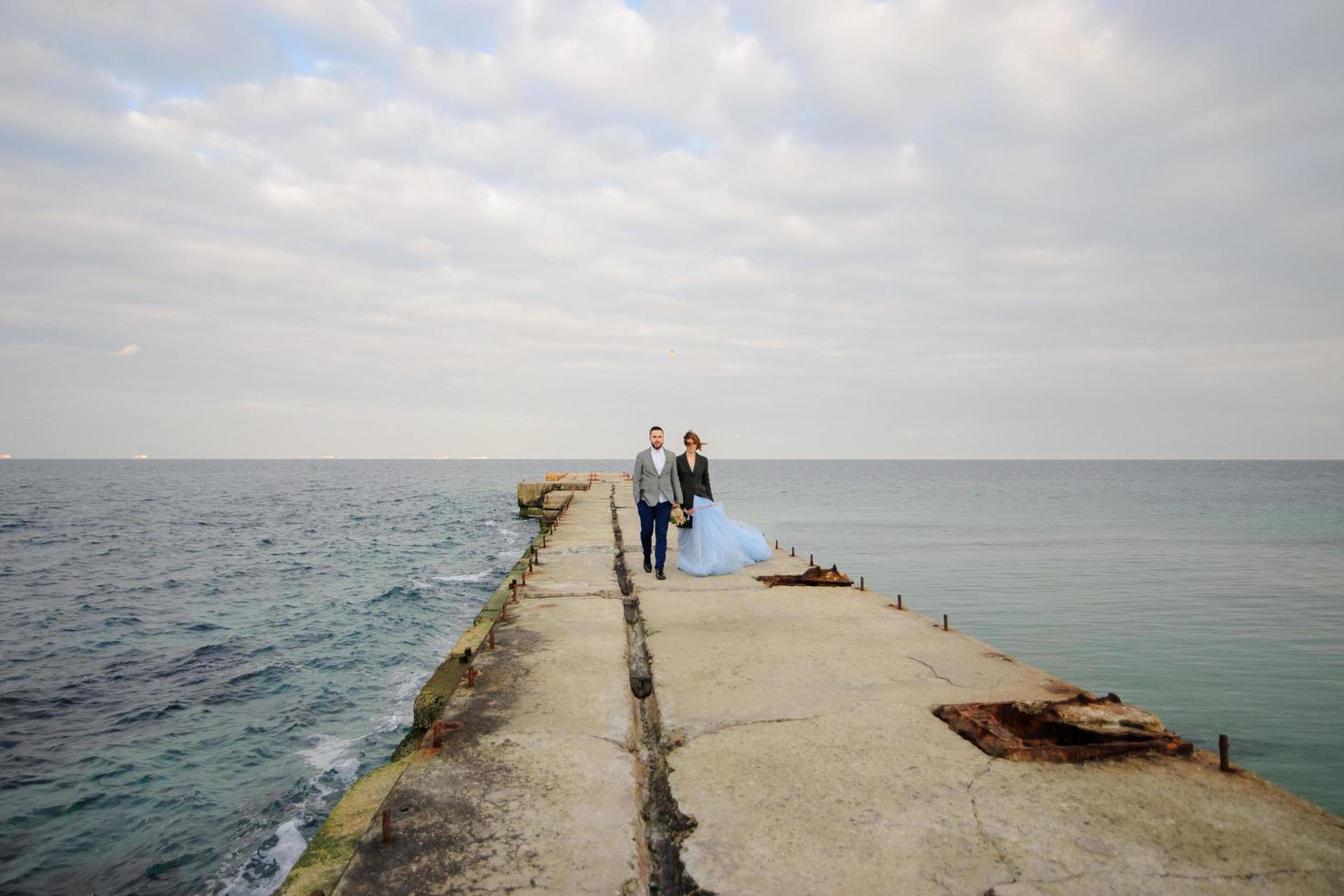 séance photo de mariage d'un couple au bord de la mer. robe de mariée bleue sur la mariée.