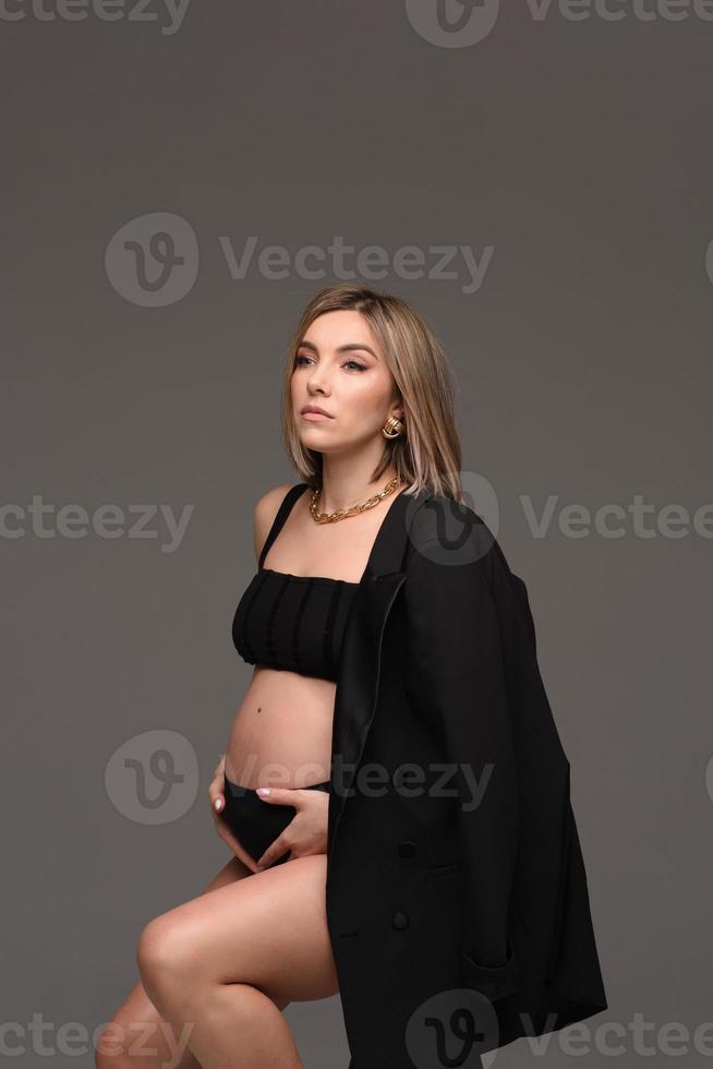 Enceinte femme dans noir robe et détient mains sur gonflé ventre